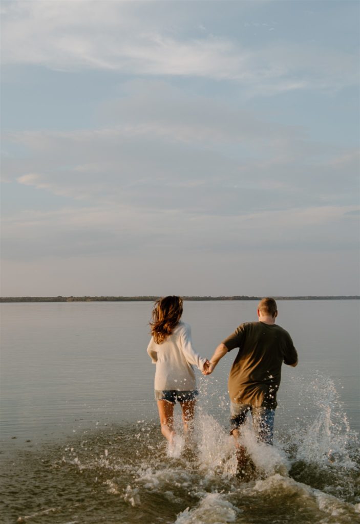 Couple running into Lake Tawakni during engagement photos.