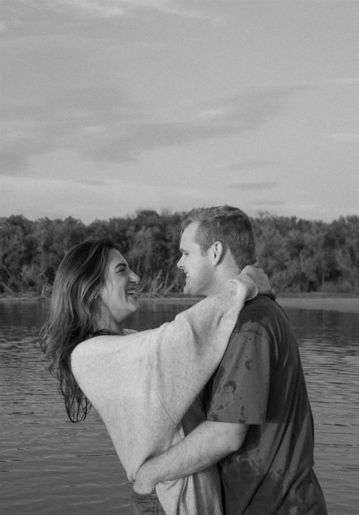 Couple laughing with each other during engagement photos at Lake Tawakoni in black and white.