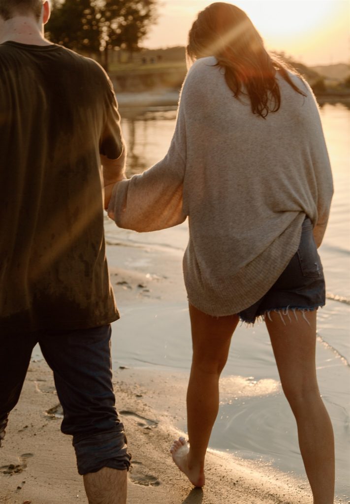 Couple walking on beach at Lake Tawakoni during golden hour.