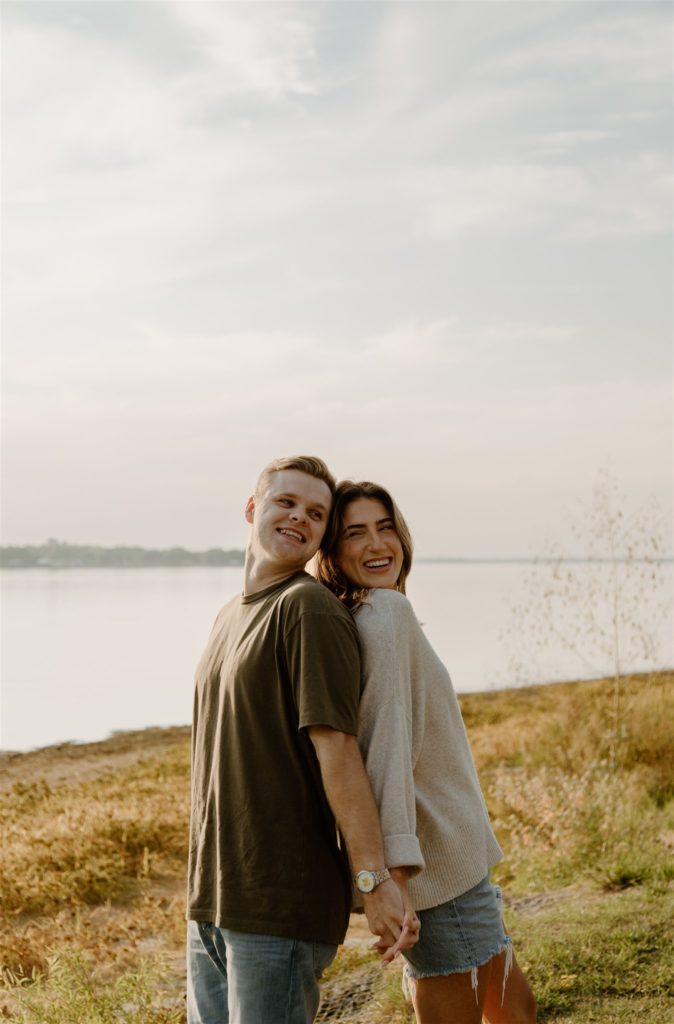 Couple laughs back to back during engagement photos at Lake Tawakoni State Park.