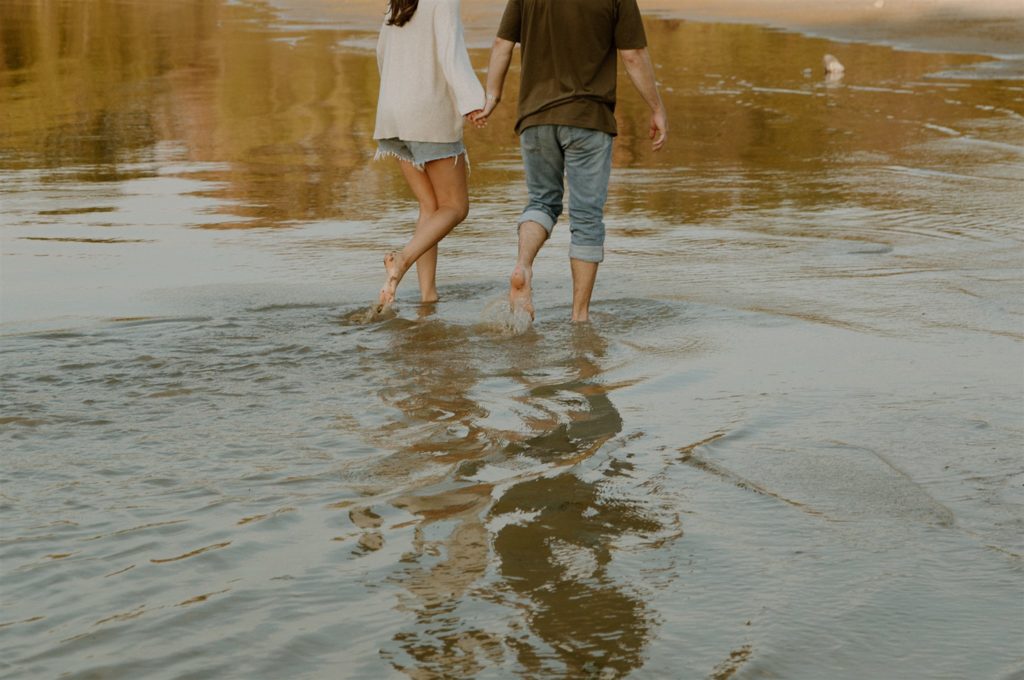 Couple walking in lake during engagement photos.