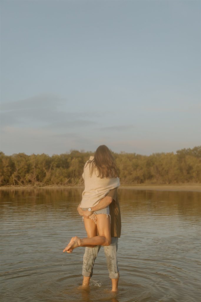 Couple spinning around in the water at Lake Tawakoni State Park during engagement photos.