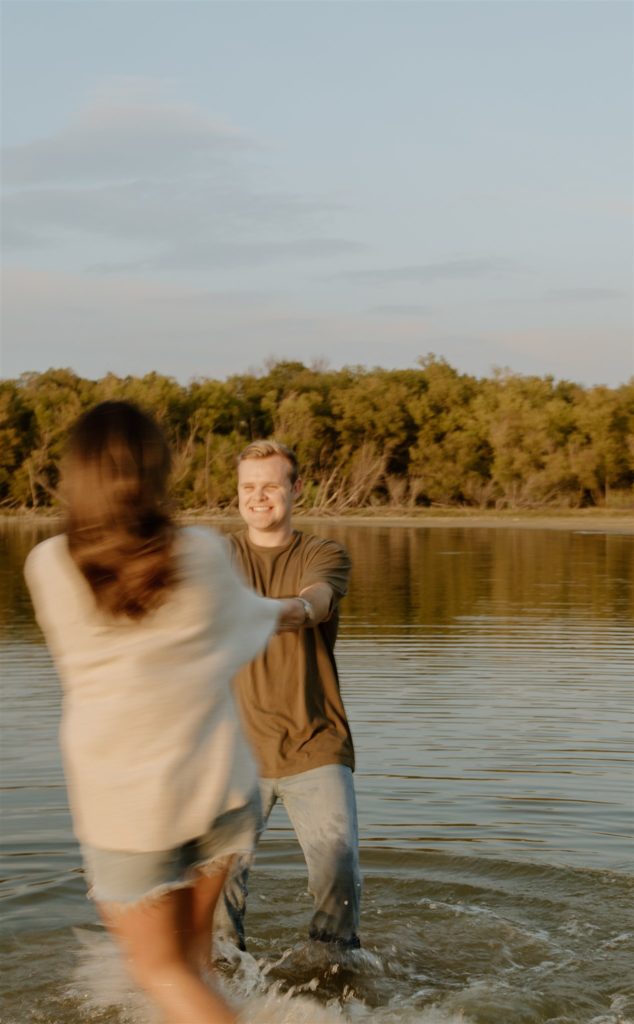 Guy spins girl around in lake during engagement photos.