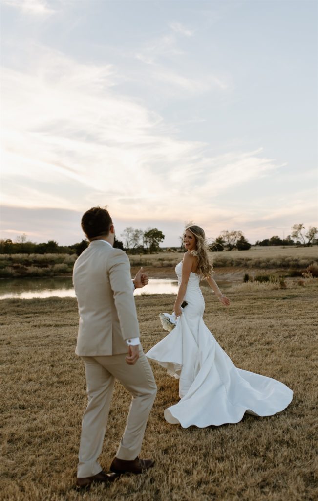 Groom playfully chases Bride during golden hour wedding portraits.