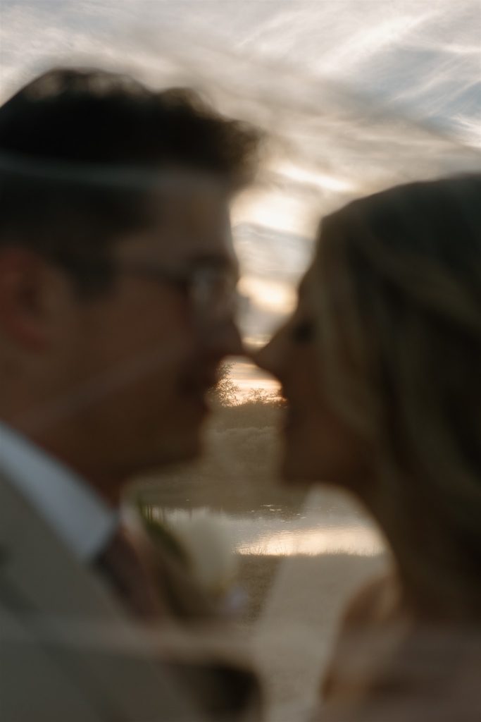 Bride and groom portraits under veil during golden hour after at wedding.