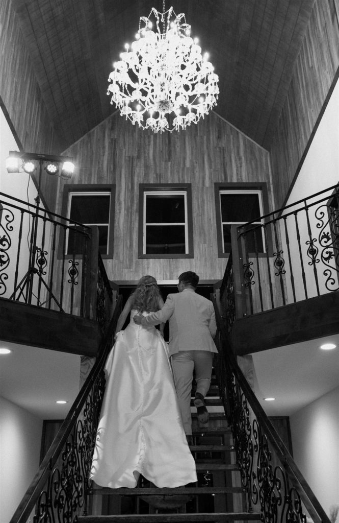 Bride and groom walking on grand staircase at texas wedding reception.