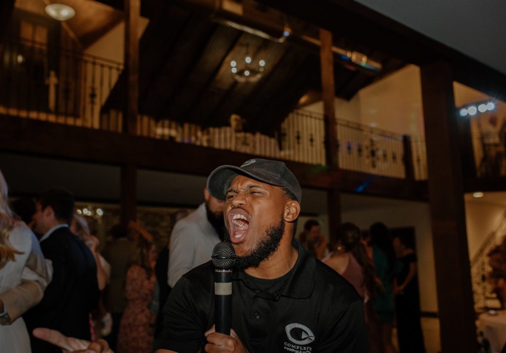 DJ Michael with Complete Weddings & Events sings into microphone during texas wedding reception.