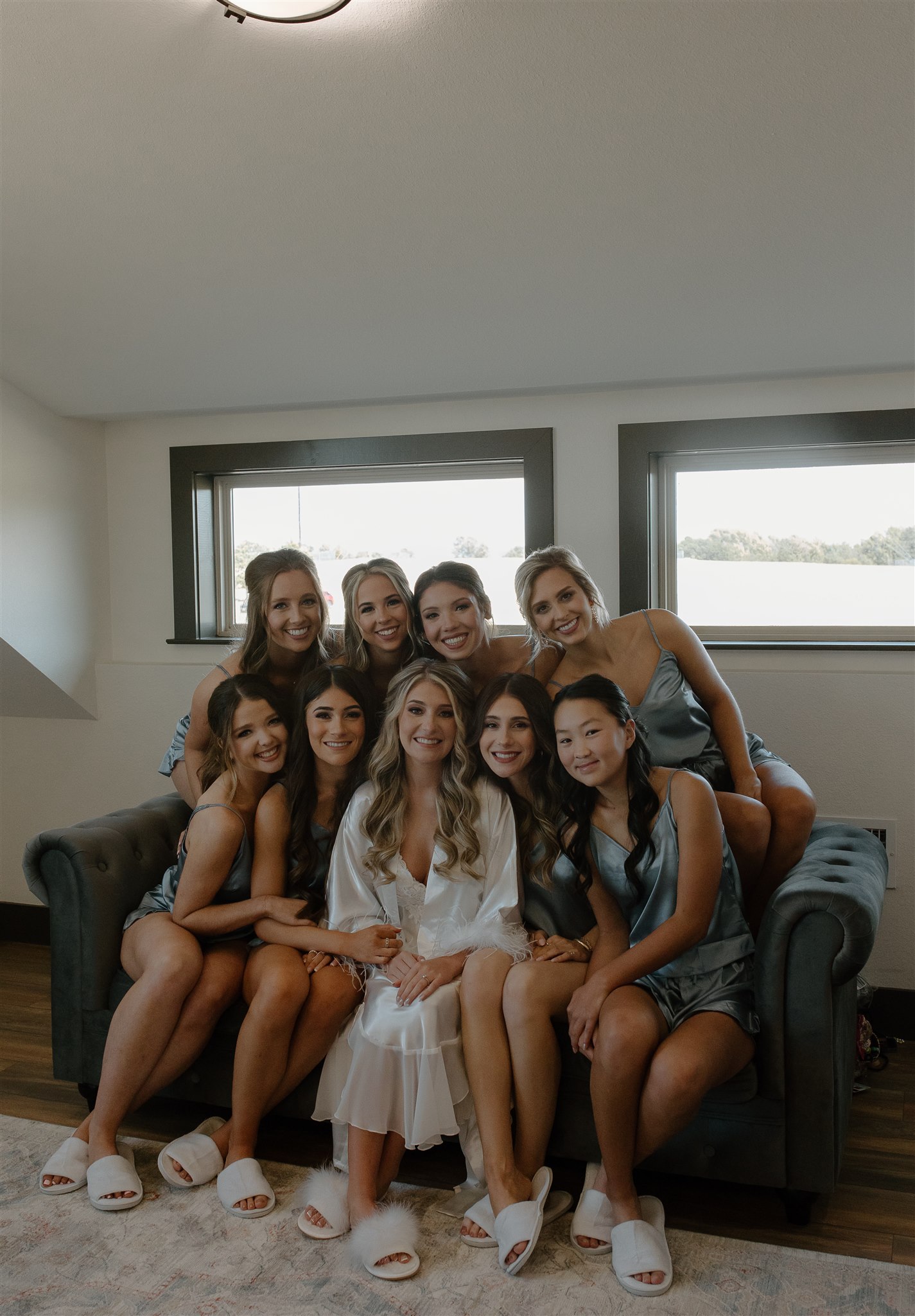 Bridal party sits on couch smiling at Texas wedding venue.