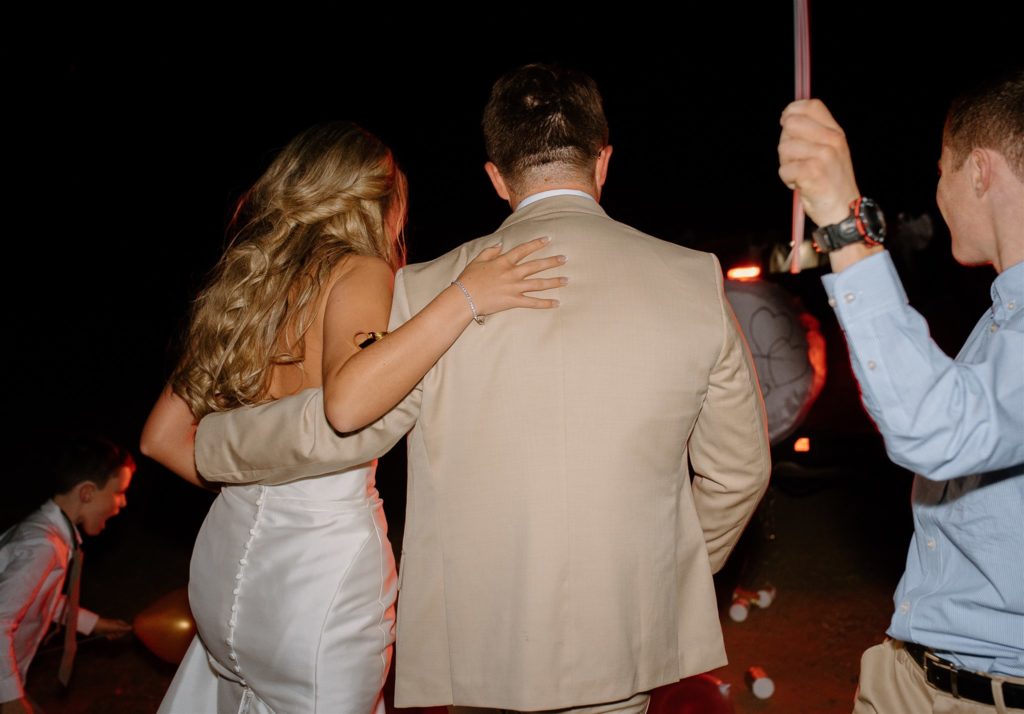 Bride and groom exit texas wedding reception in red Jeep Wrangler decored.