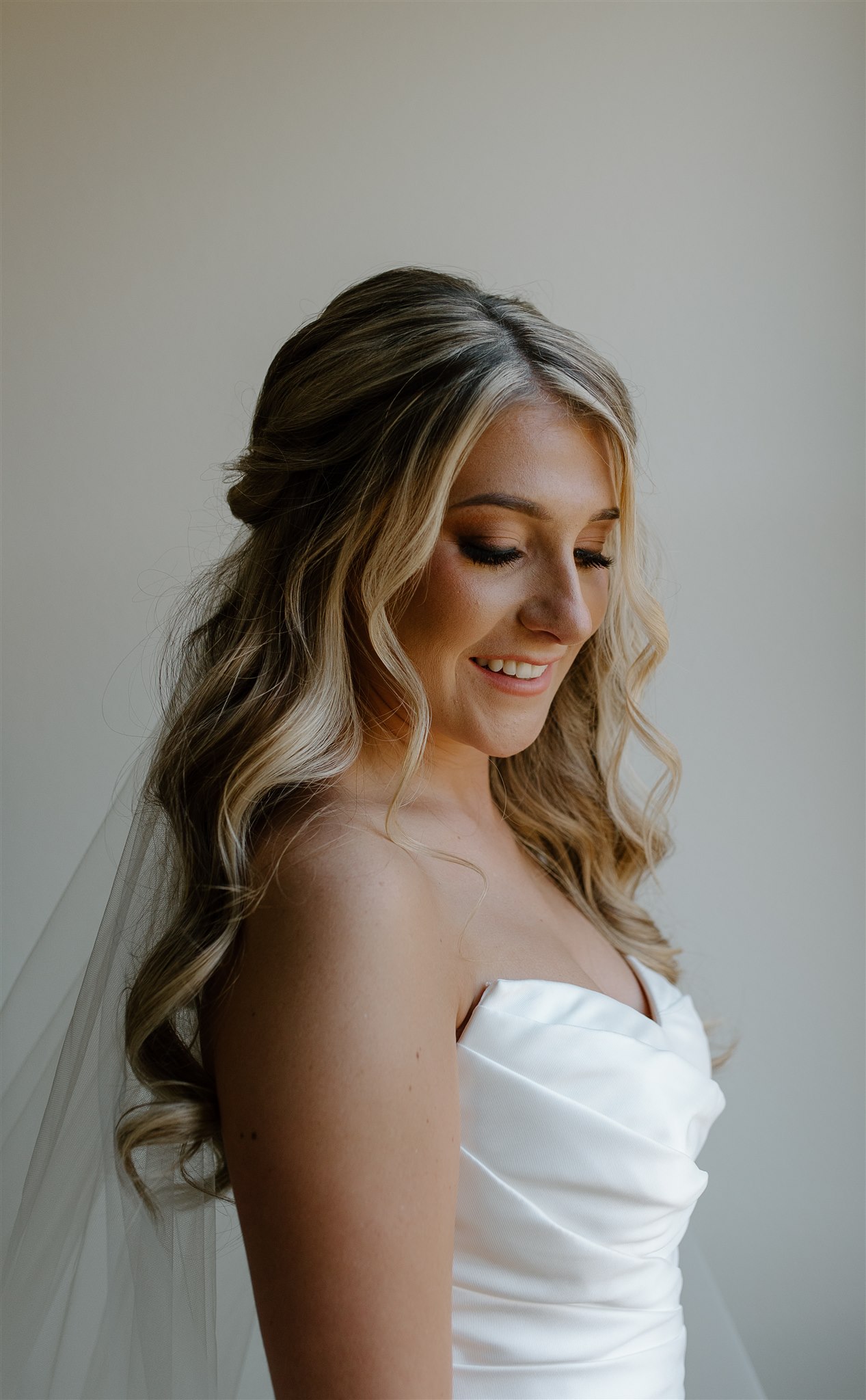 Bride smiles at shoulder in front of a wedding overlooking a Texas vineyard.