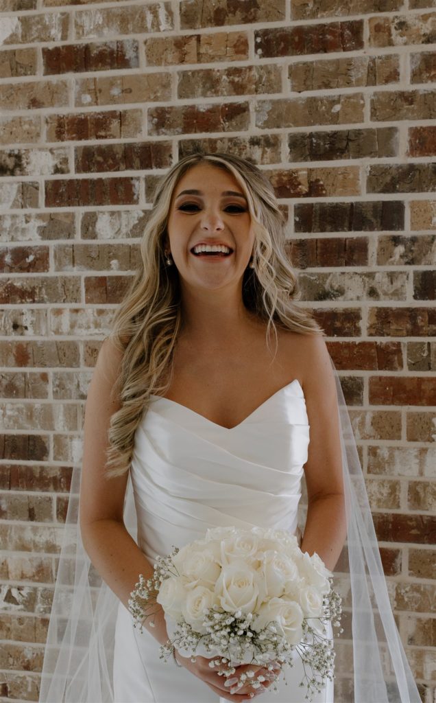 Bride laughs at camera with modern dress and detailed veil.