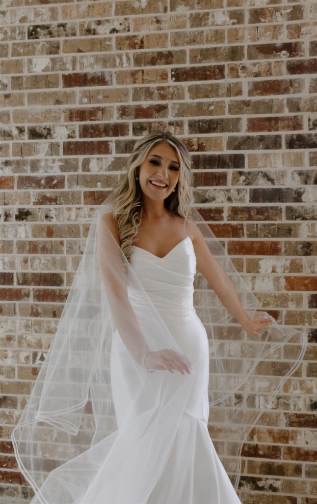 Bride dances with veil during indoor bridal portraits.