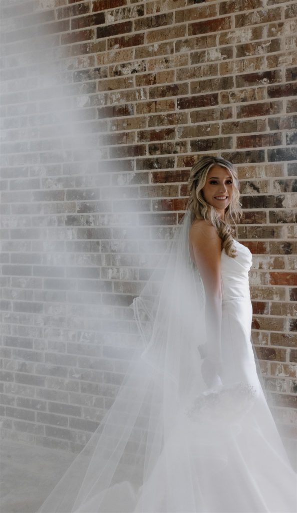 Bride looks back over shoulder towards camera with a big smile.