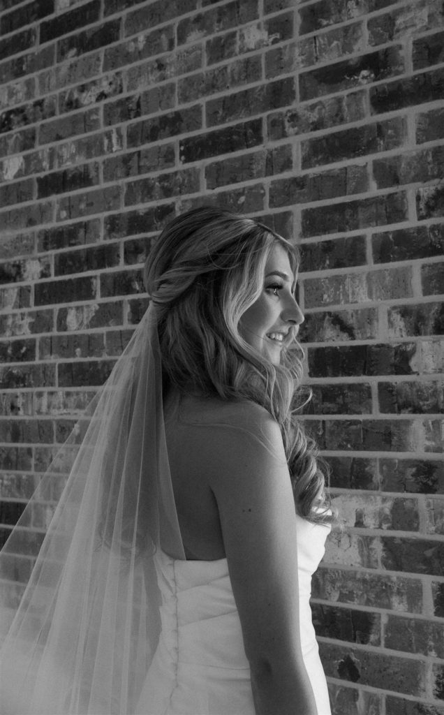 Bride gazes out of window in black and white.