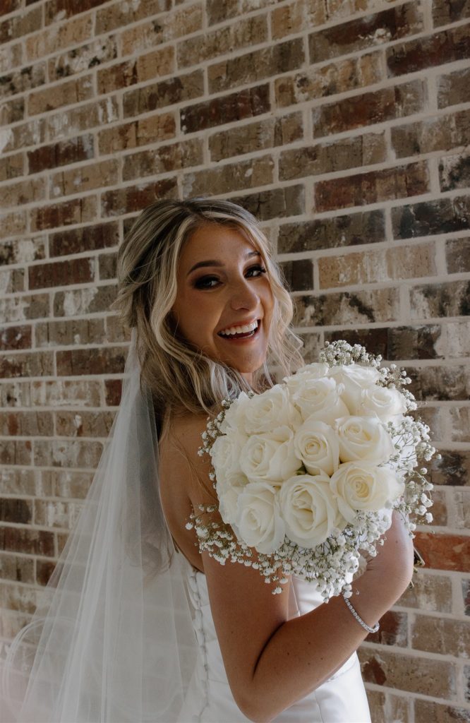 Bride smile with bouquet during Texas wedding venue.