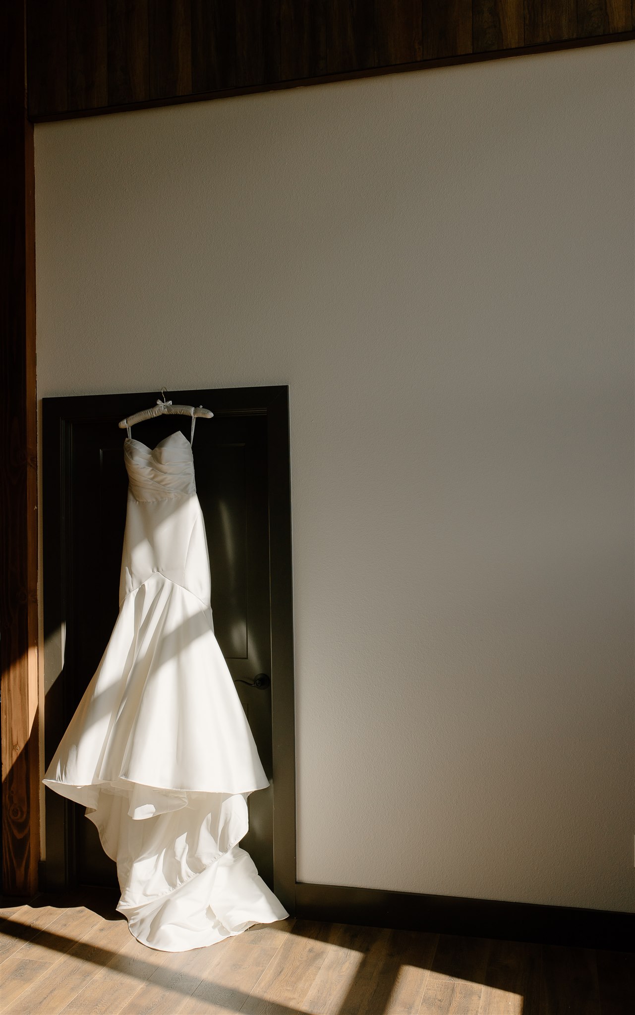 Modern wedding dress hanging on doorframe.