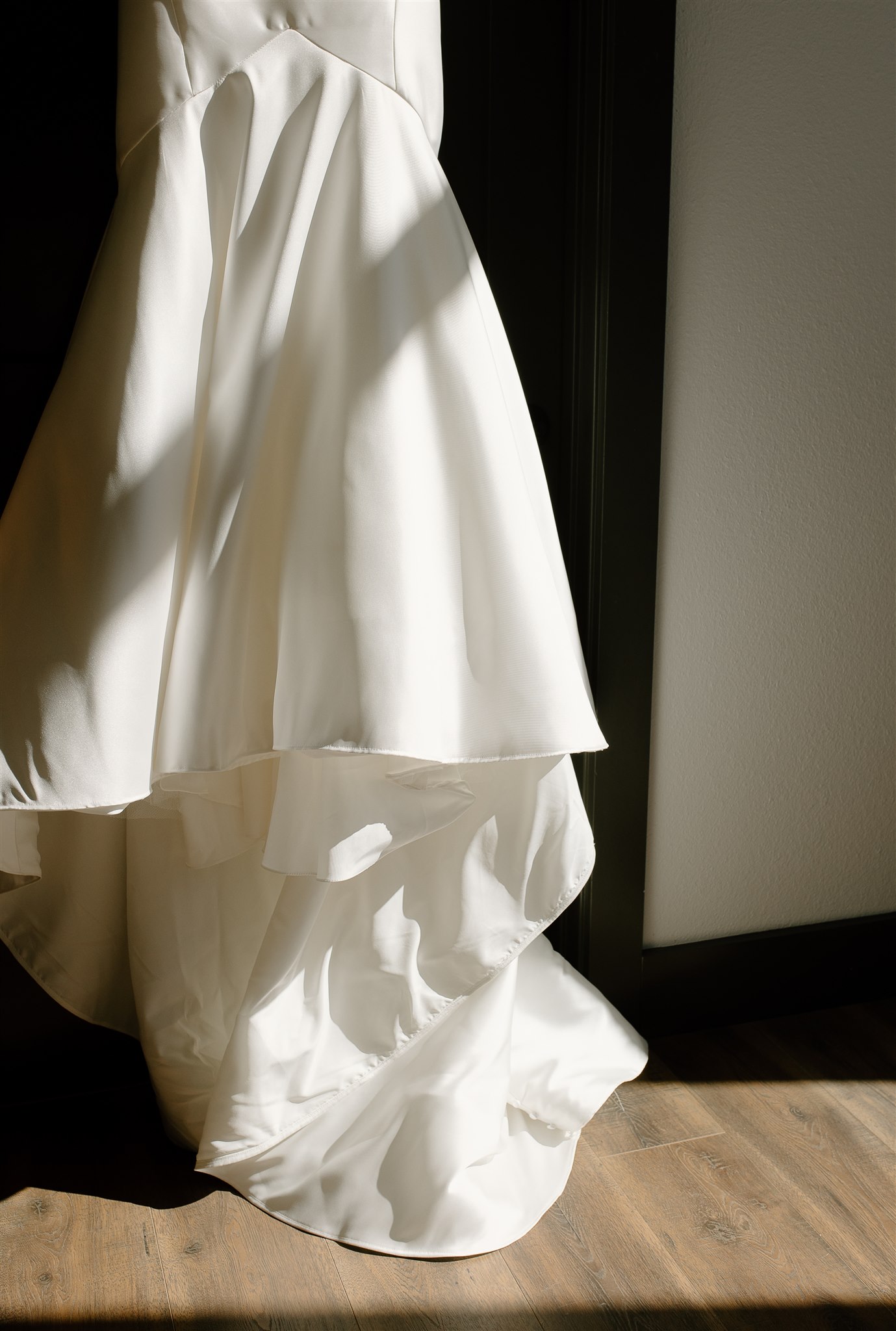 Modern Wedding Dress hanging in doorway with shadows.