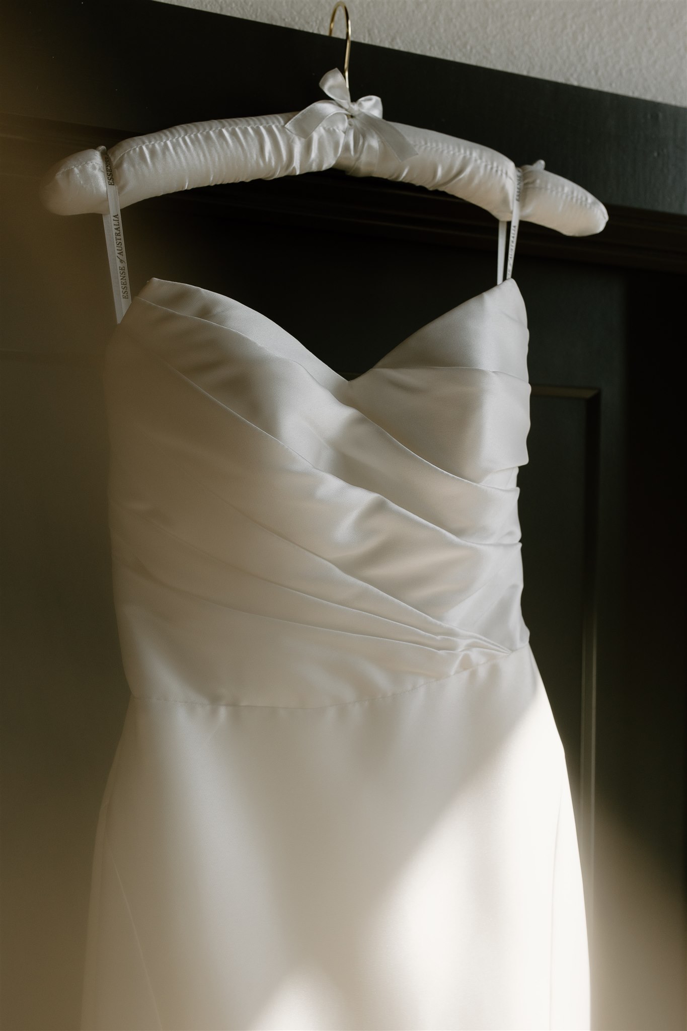 White wedding dress details hanging from doorway.