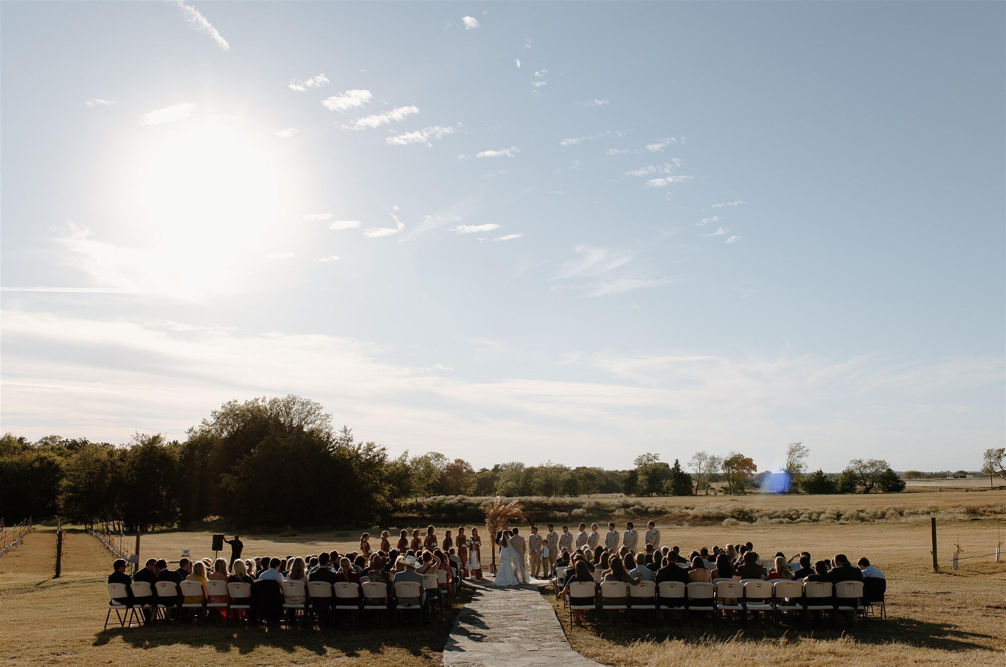 Texas outdoor wedding ceremony with guests seated near vineyeard at texas wedding venue.