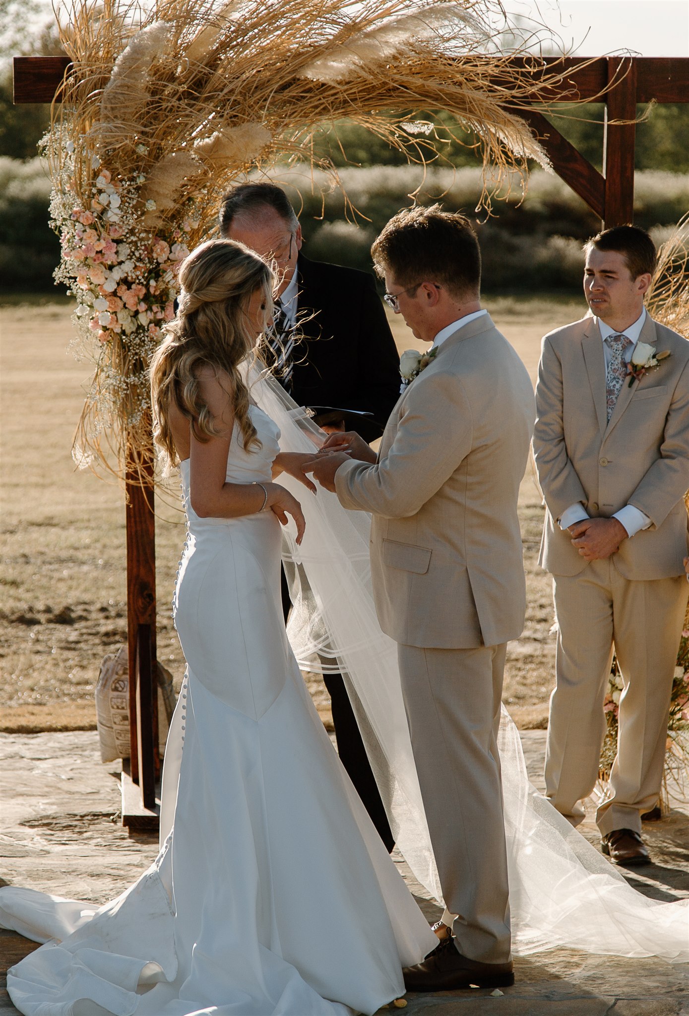 Groom places wedding ring on Bride's ring finger during texas wedding ceremony.