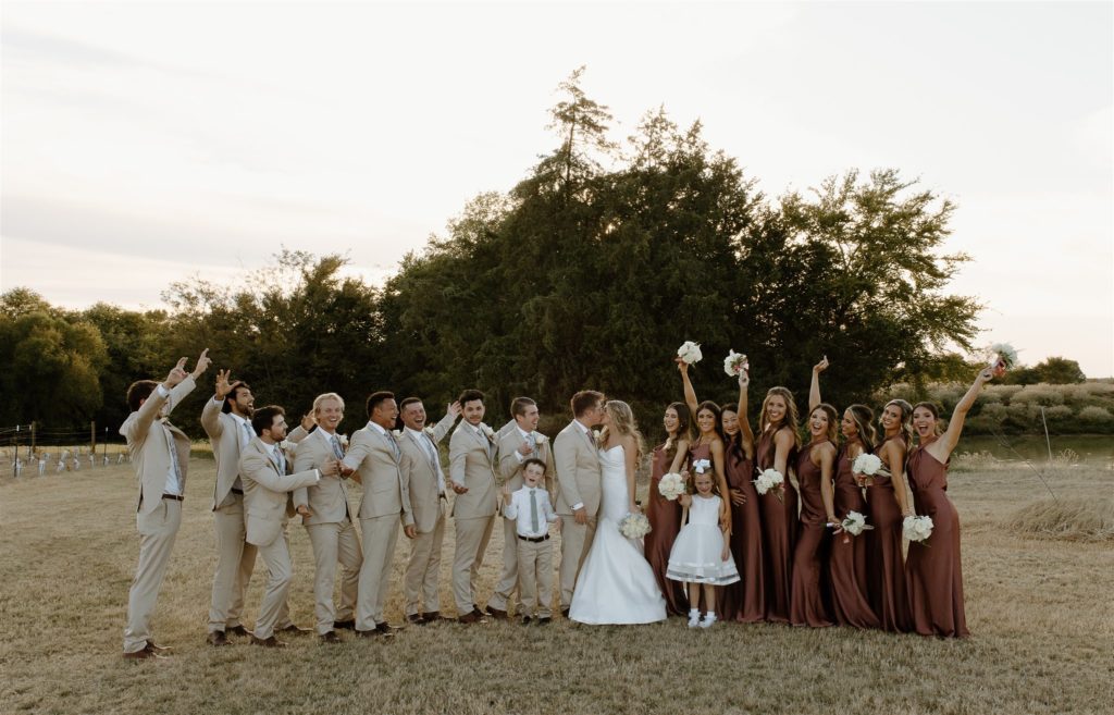 Texas wedding party celebrates the bride and groom as they kiss after texas wedding.