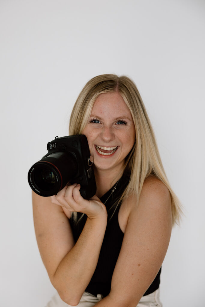 DFW Wedding Photographer holds camera close to face and laughs for headshot photo.