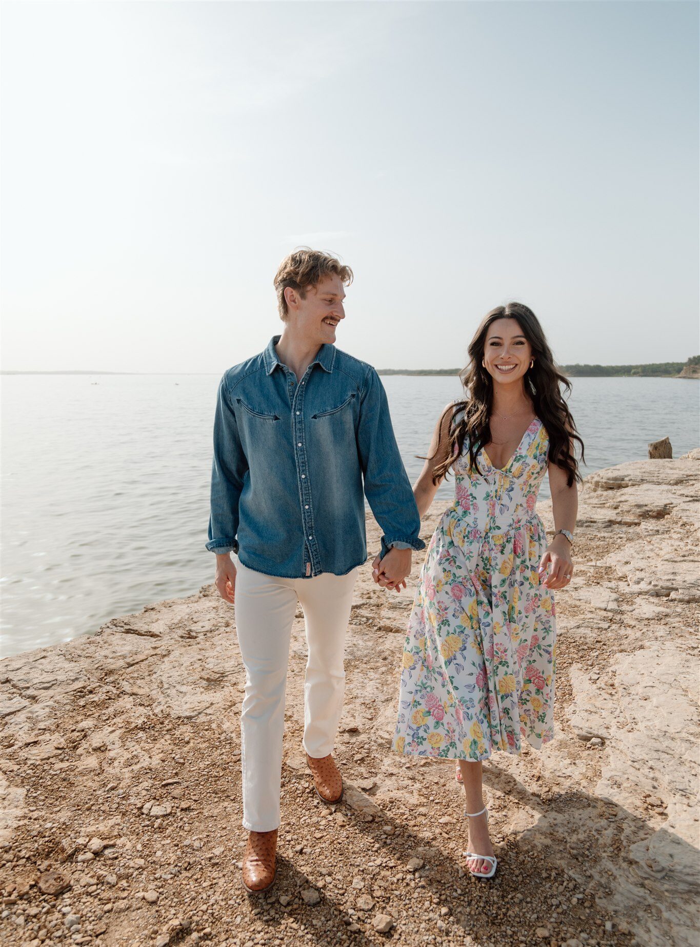 A newly engaged couple walk along the rocky edge during their Rockledge Park engagement session in Grapevine, Texas.